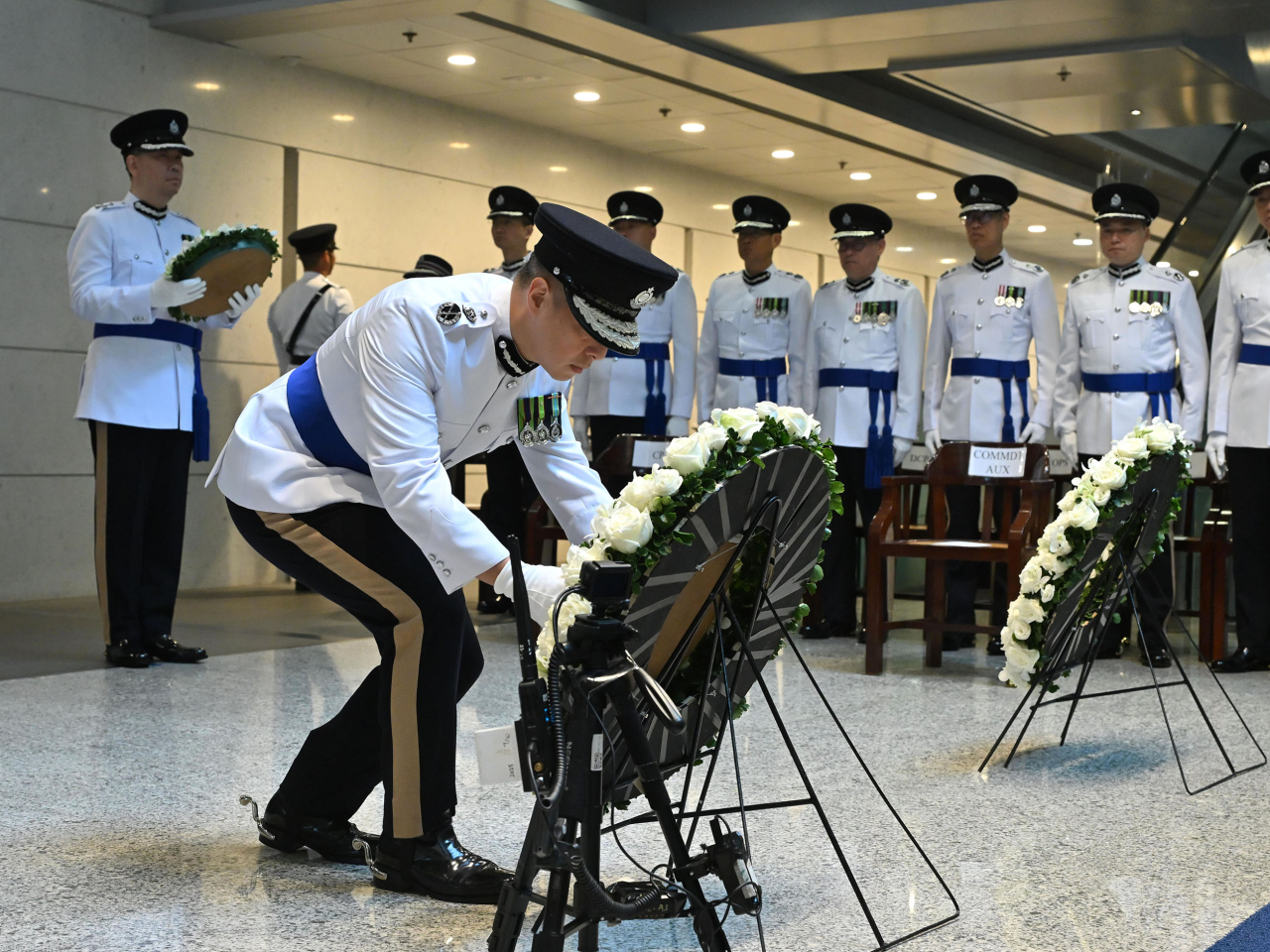 周一鳴於刻有殉職人員姓名的警隊紀念牆前獻上花圈。（政府新聞處）