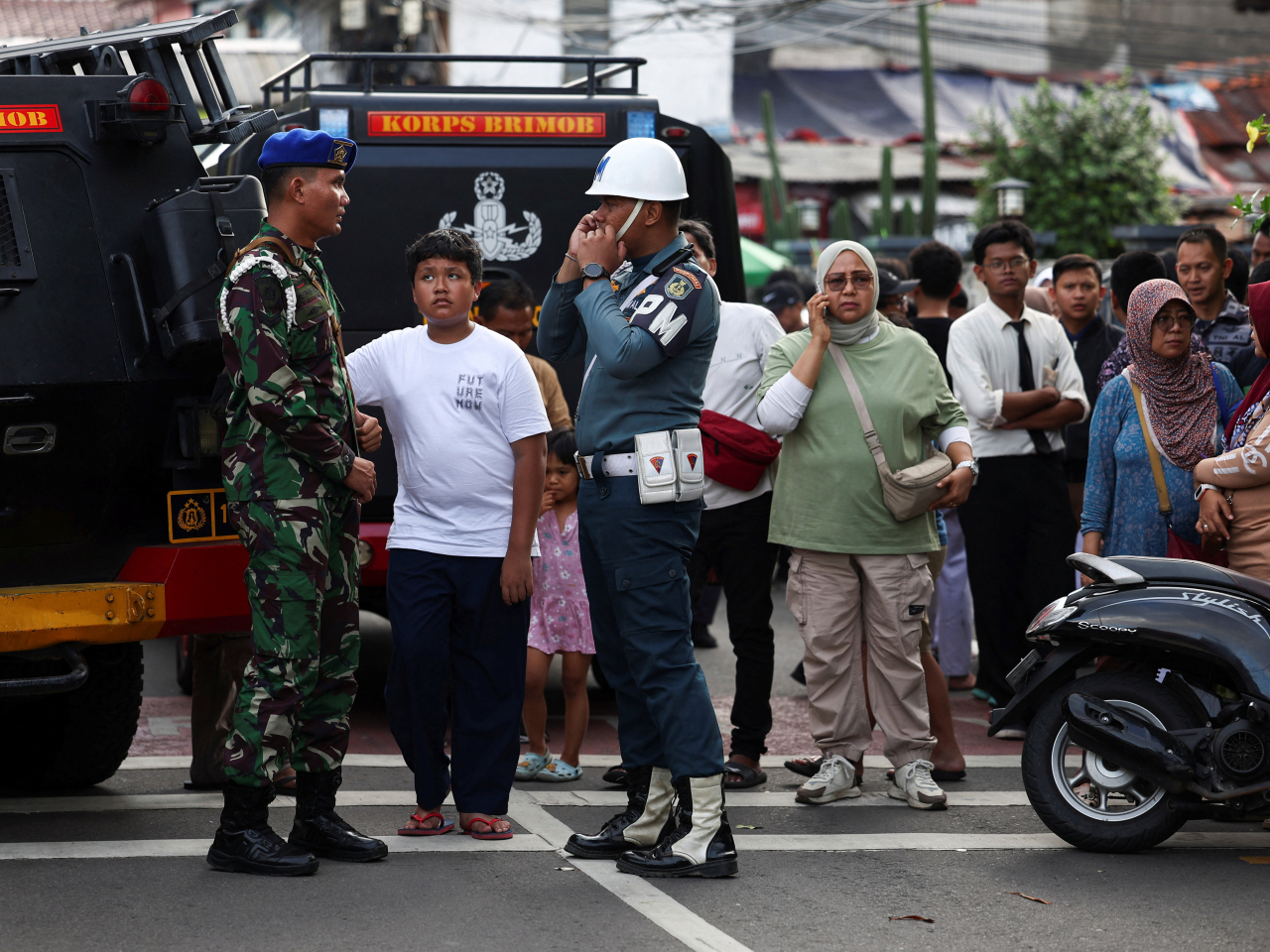 Military personnel guard as residents gather near the area after an explosion occurred at a school complex in Jakarta. Photo: Reuters
