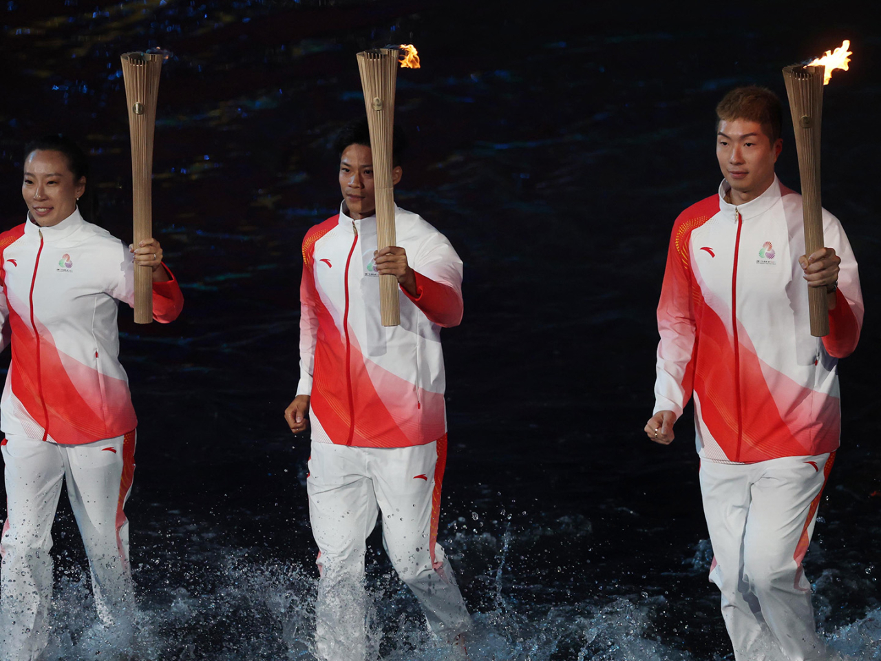 港隊劍擊代表、奧運金牌得主張家朗，廣東百米亞洲紀錄保持著蘇炳添及澳門的亞運武術長拳金牌得主李禕，涉水接最後一棒。（新華社）