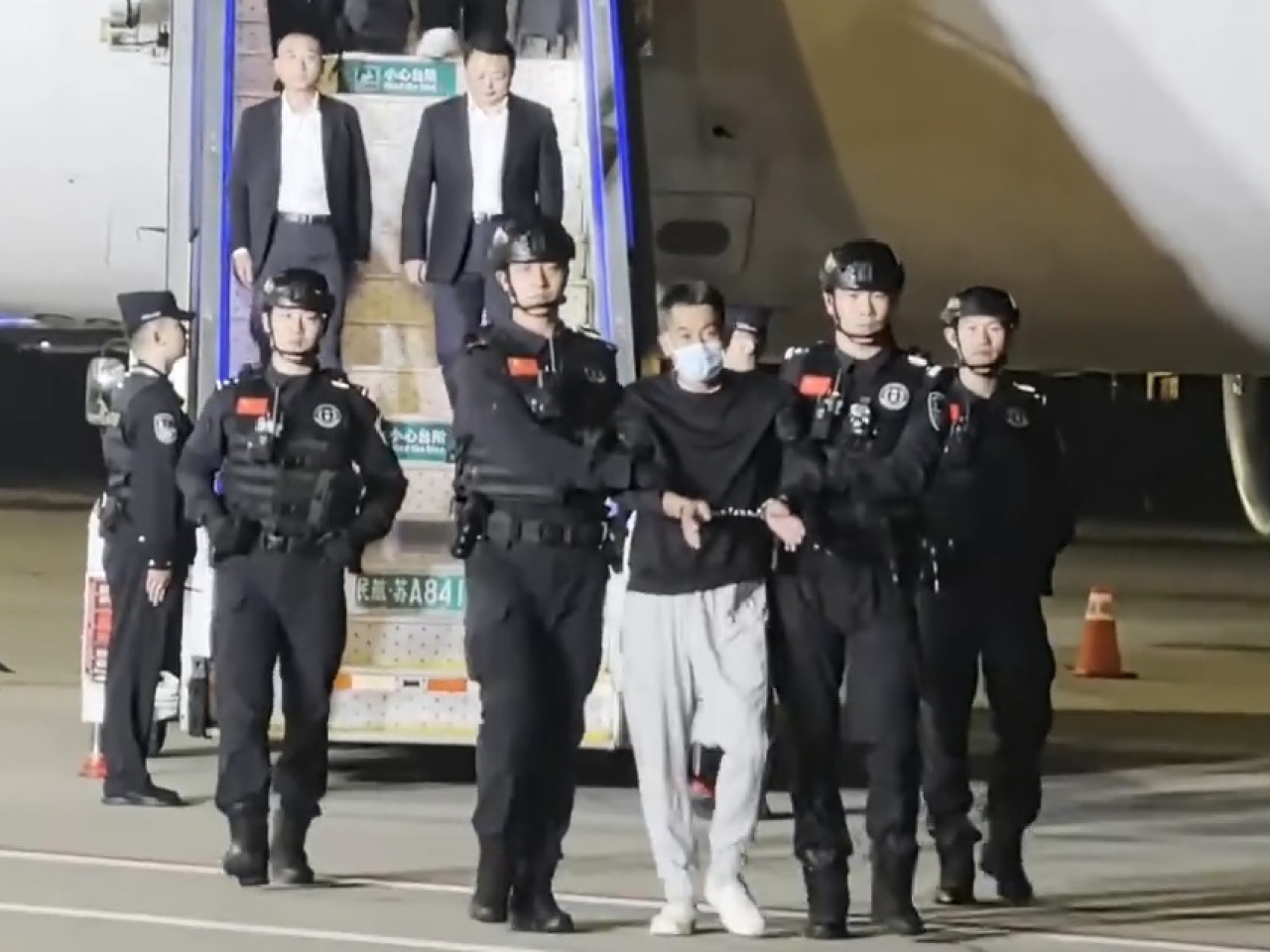 載著佘智江的客機晚上降落南京祿口國際機場，佘智江雙手鎖上手扣。(央視截圖)