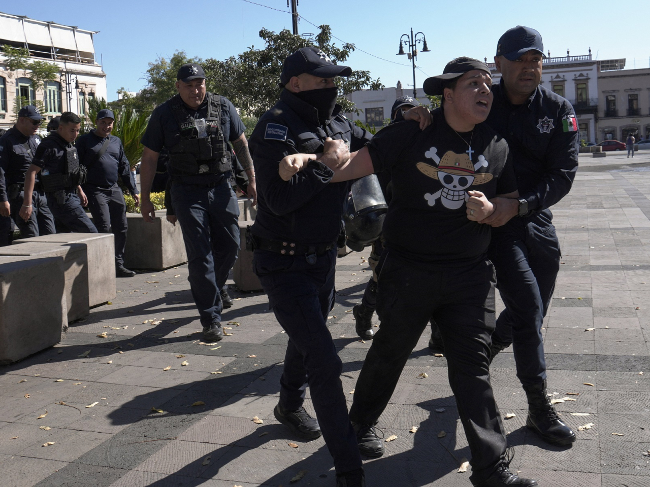 A demonstrator wearing a One Piece t-shirt is held by police officers during a protest of supporters of the recently killed Michoacan Mayor Carlos Manzo. Photo: Reuters
