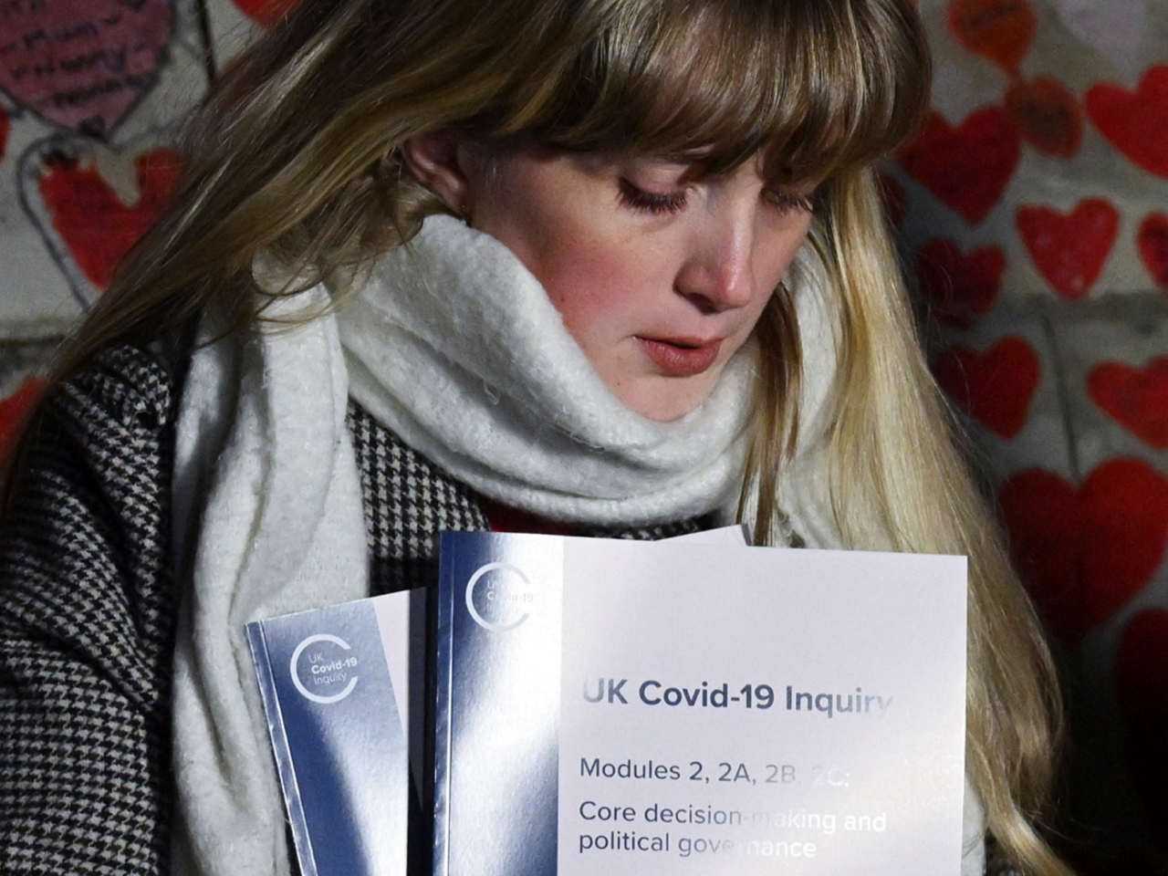 英國一個委員會公布新冠期間政府應對措施的報告。圖為手持報告副本的疫情受害者家屬。（路透社）