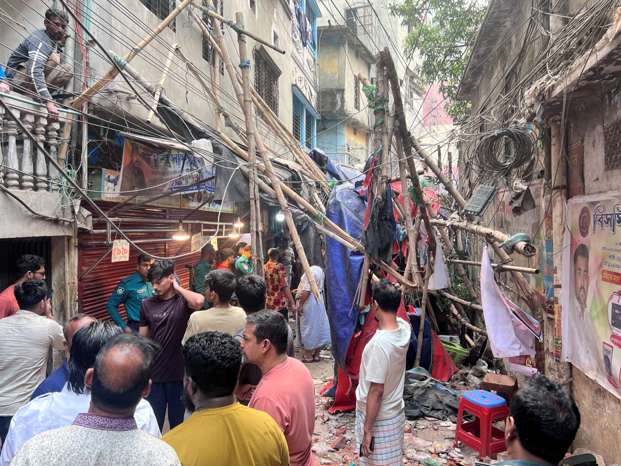 Residents find relative safety in an alley near fallen scaffolding following an earthquake in Dhaka. Photo: Reuters