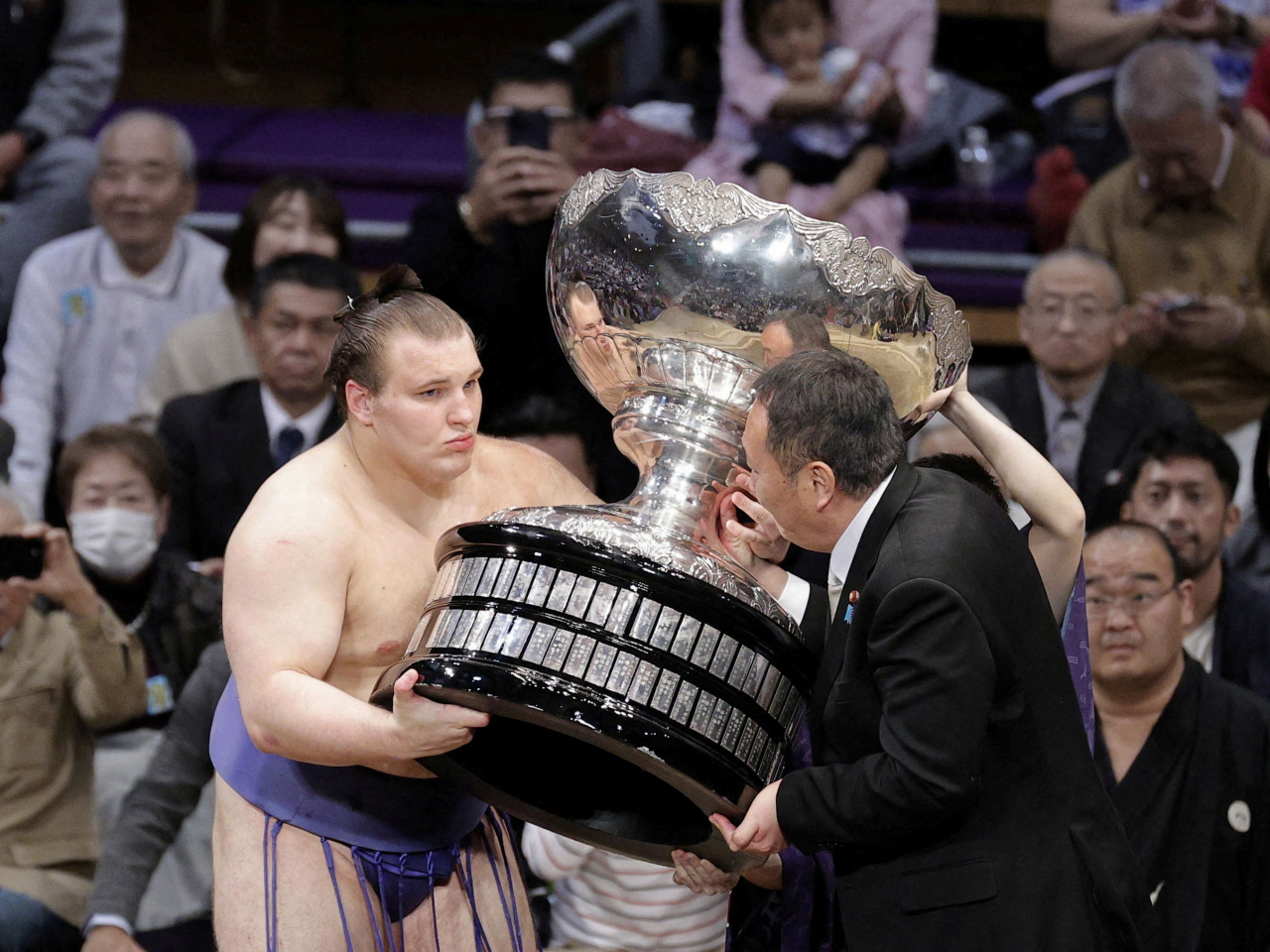 Ukrainian sumo wrestler Aonishiki Sekiwake, aka Danylo Yavhusishyn, gets an outsised Prime Minister's Cup after winning the Fukuoka tournament. Photo: Reuters