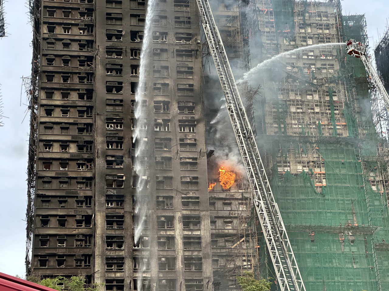 Flames are still visible in several units more than a day after the deadly fire broke out at Wang Fuk Court. Photo: RTHK