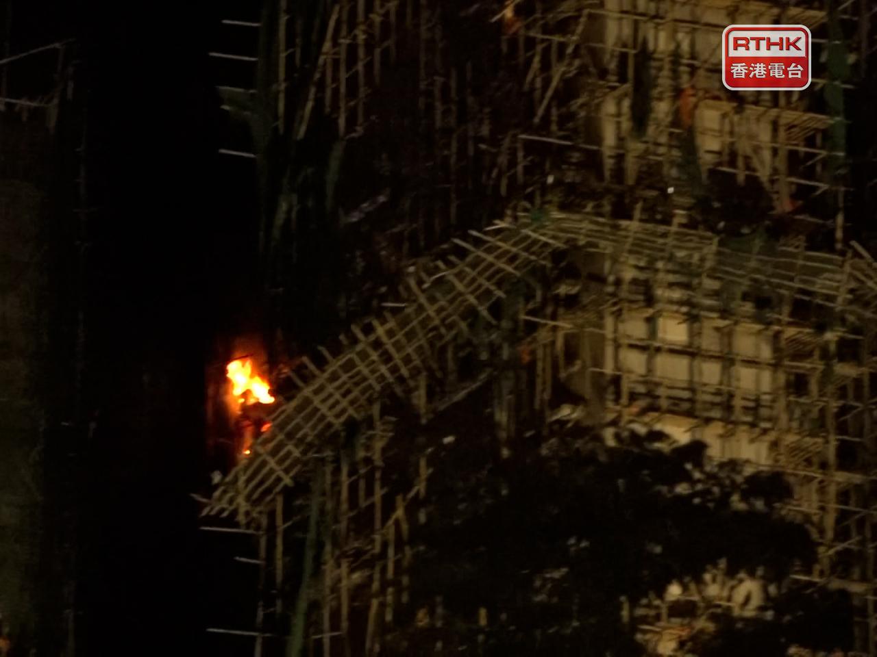 消防繼續在火場灌救，有樓宇部分高層單位深夜時火勢再次加劇。(陳韋丞攝)
