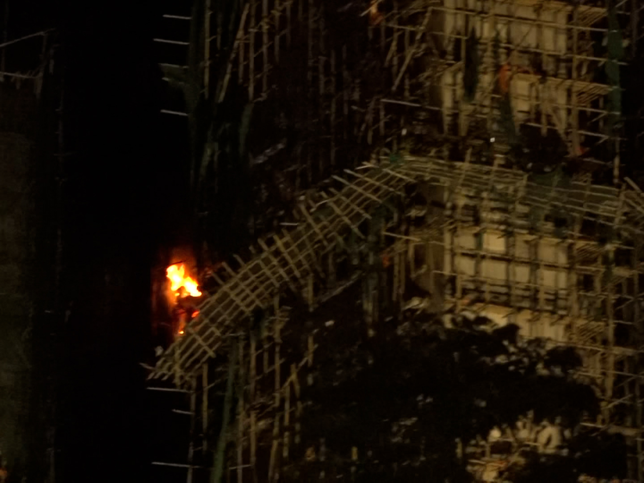 消防繼續在火場灌救，有樓宇部分高層單位深夜時火勢再次加劇。(陳韋丞攝)