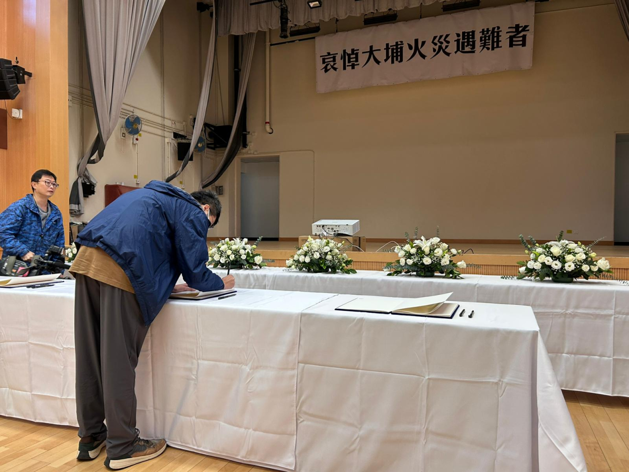 弔冊處前方擺放了白花，背後掛上悼念橫幅。(林漢山攝)