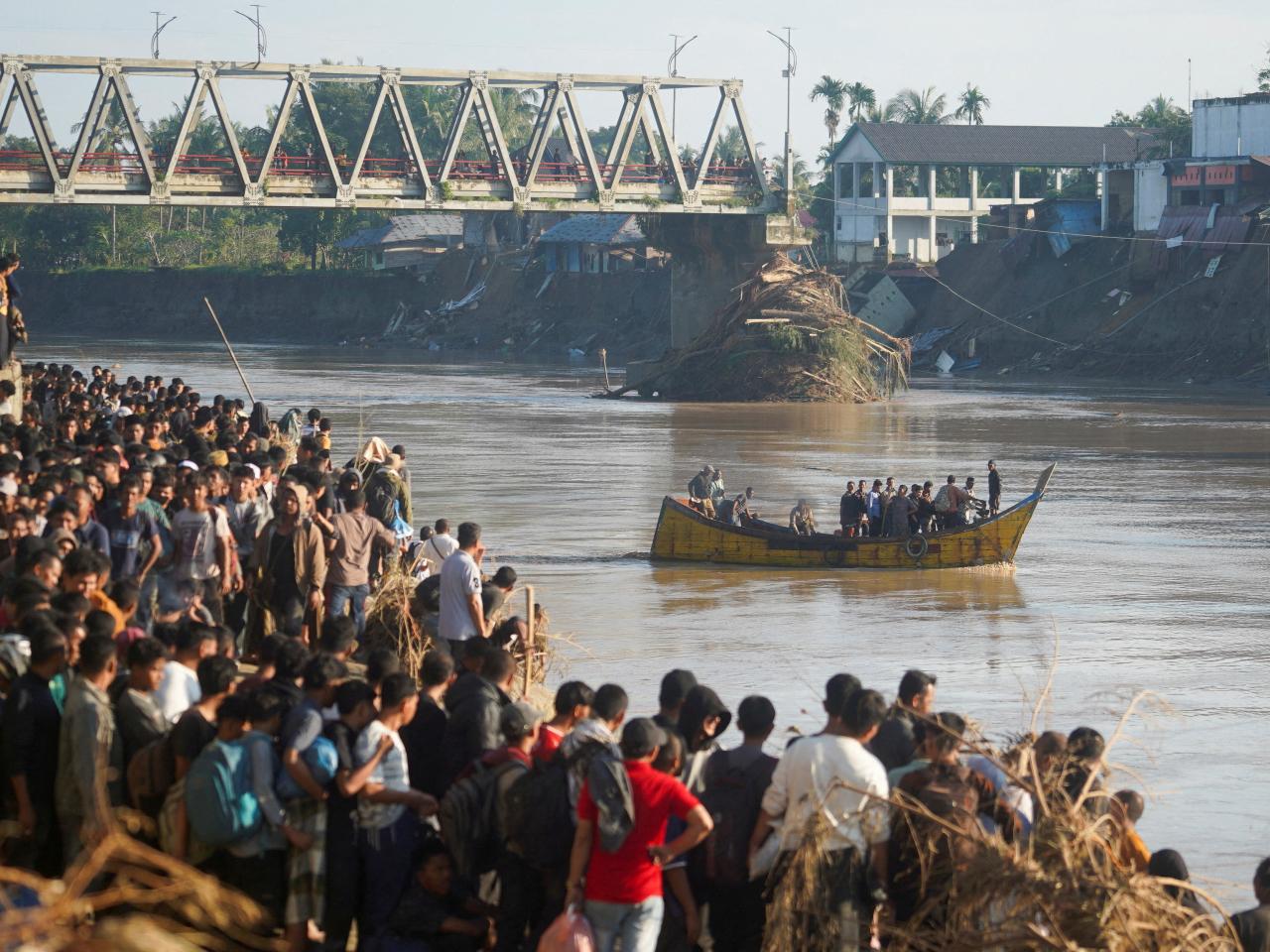 Indonesians in Bireuen Regency, Aceh, wait for their turn at a river crossing following damage to a bridge. Photo: Reuters