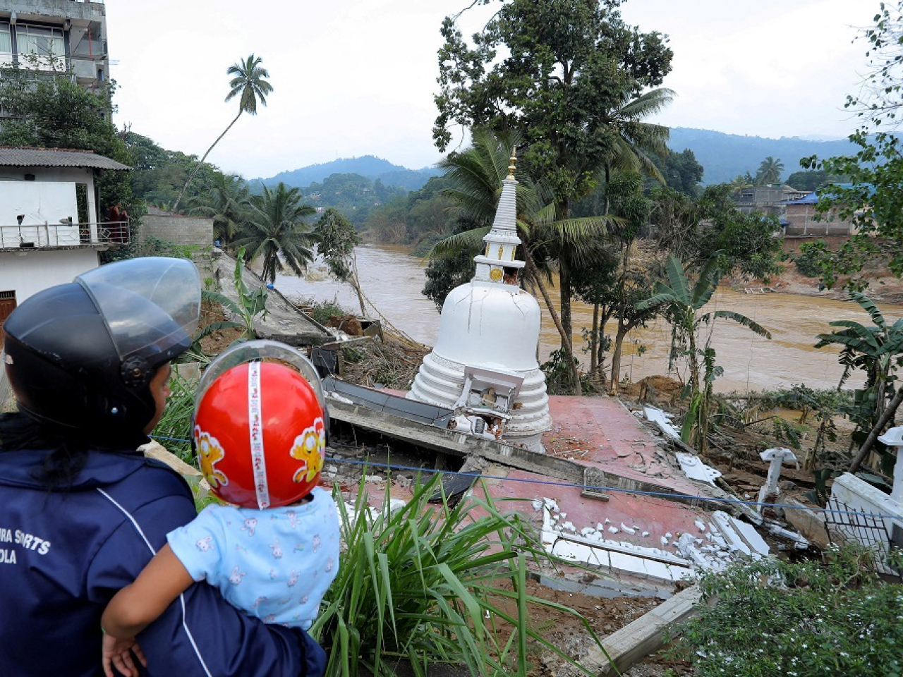 A woman holding a child gazes at a damaged temple following a landslide in the aftermath of Cyclone Ditwah in Gampola in Kandy district, Sri Lanka. Photo: Reuters