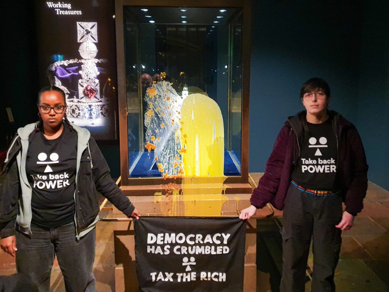 The two demonstrators unfurled a sign saying, “Democracy has crumbled. Tax the rich.” Photo: AFP