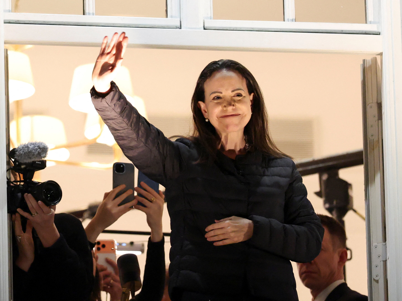 馬查多星期四凌晨現身挪威奧斯陸的酒店露台，向民眾揮手致意。（路透社）