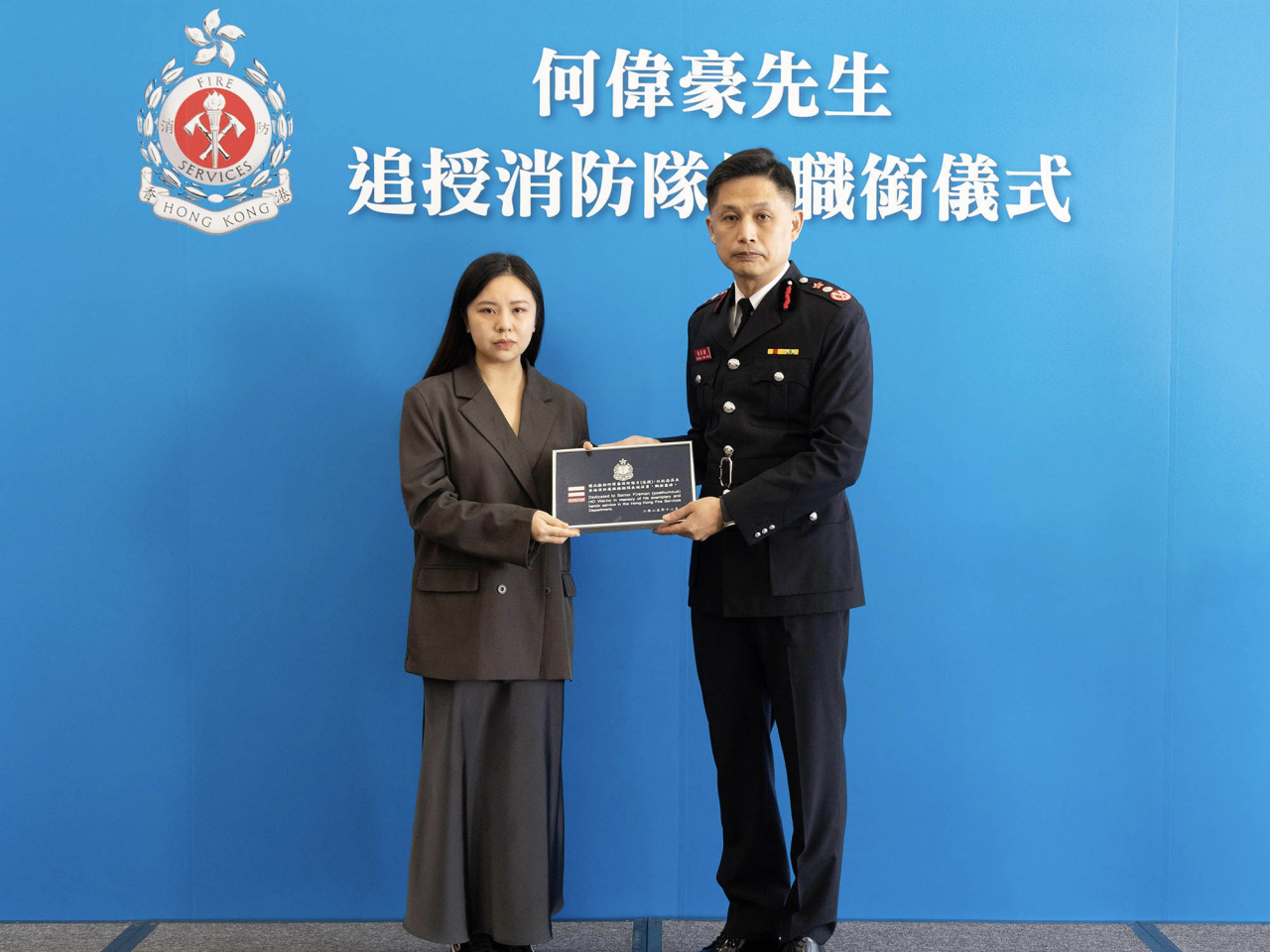 楊恩健向何偉豪頒授追授函件及消防隊目階級章刺繡，由何偉豪家人代表接受。（政府新聞處）