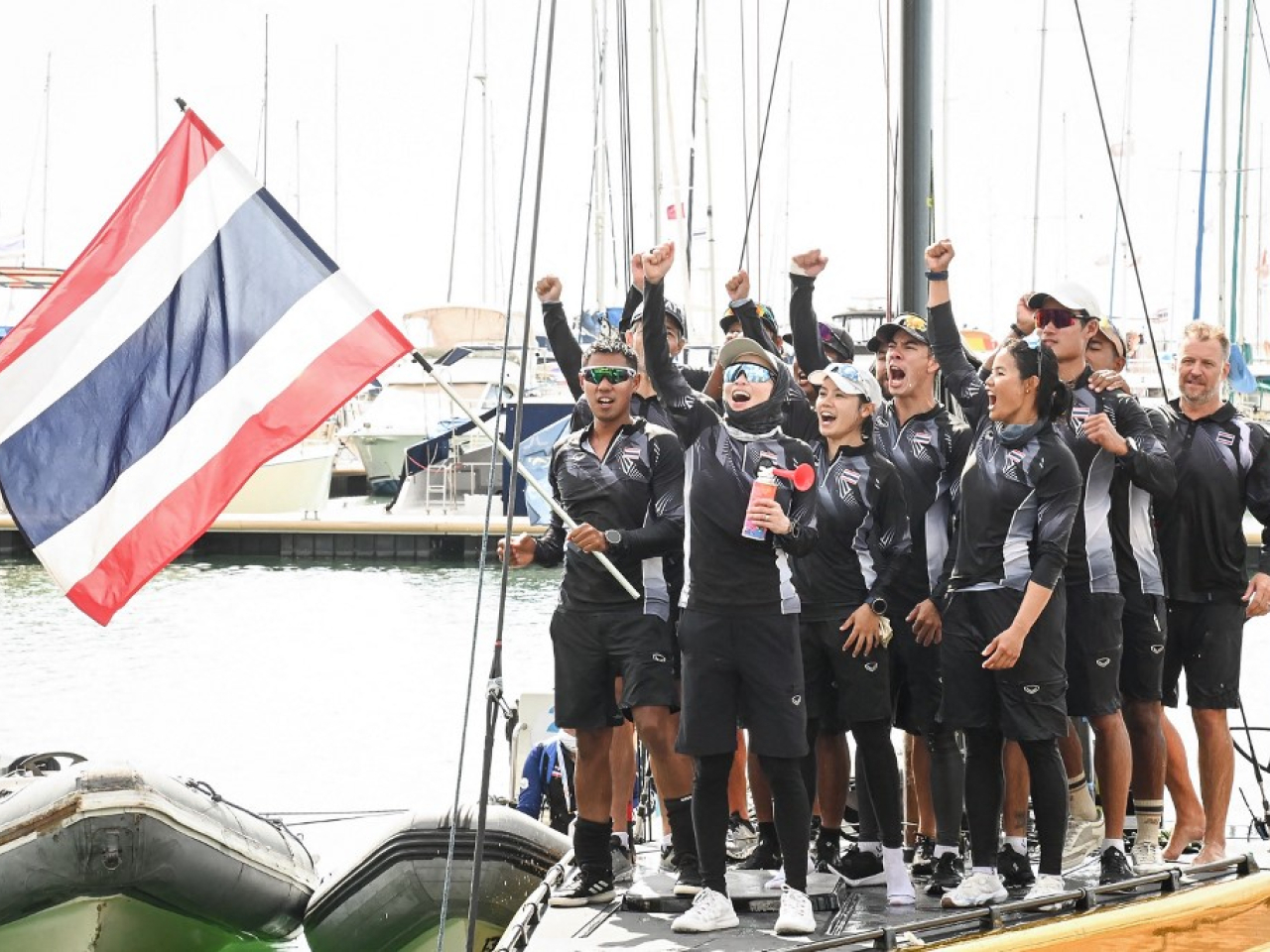 Thailand's Queen Suthida (holding the air horn) competed with nine other crew members in the mixed sailing event of the 33rd Southeast Asian Games. Photo: AFP