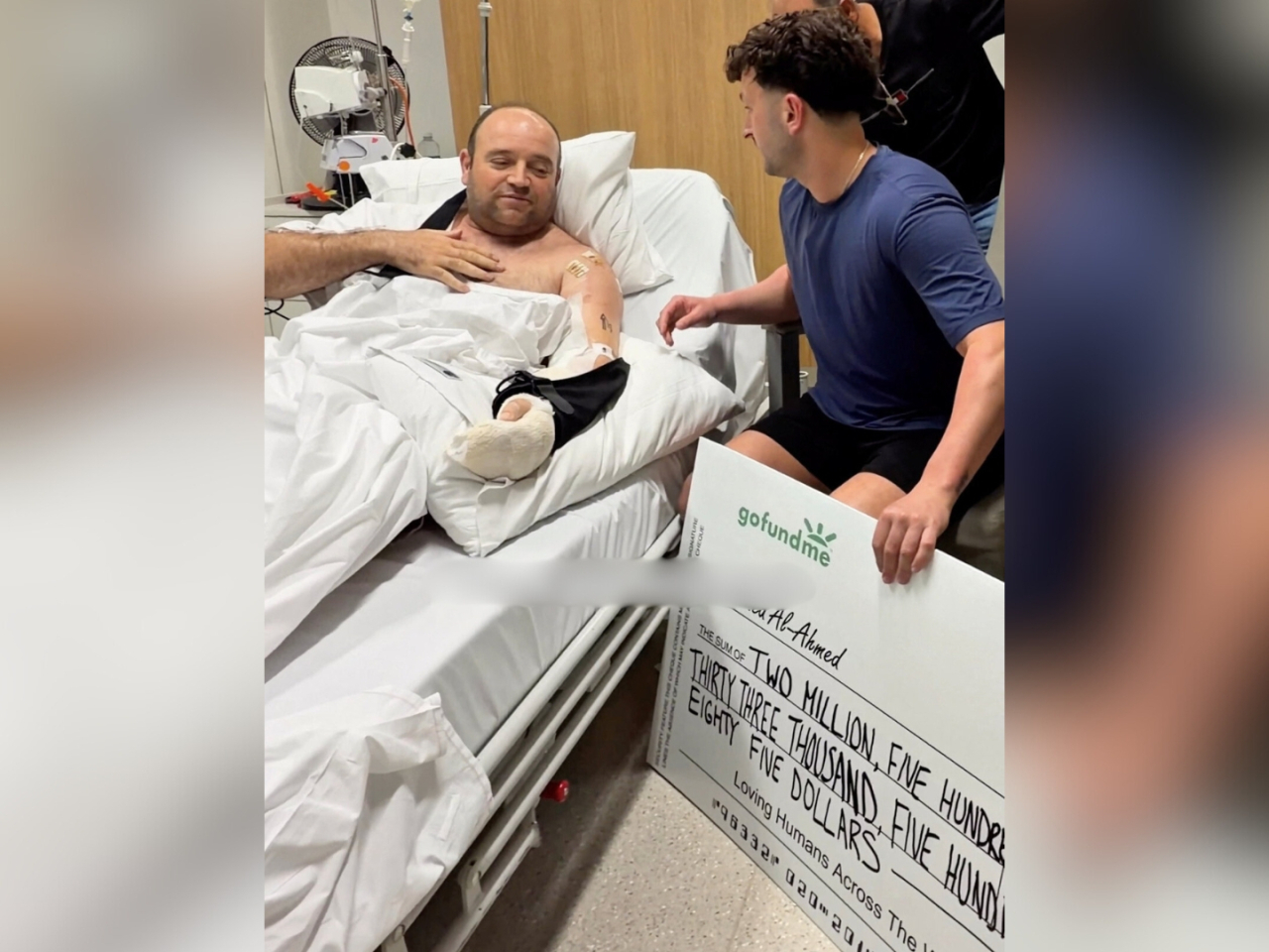 Bondi Beach hero Ahmed al Ahmed is presented with a mockup A$2.5 million cheque by social-media influencer Zachery Dereniowski at his Sydney hospital bed. Photo: Reuters