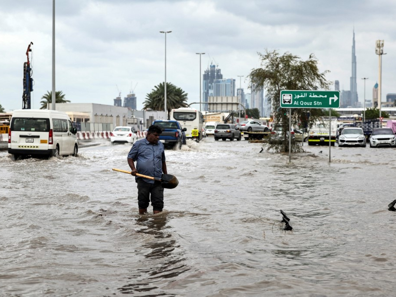 A man wades through floodwaters to clear a drain as roads leading to the Burj Khalifa in Dubai are clogged up by slow traffic. Photo: AFP