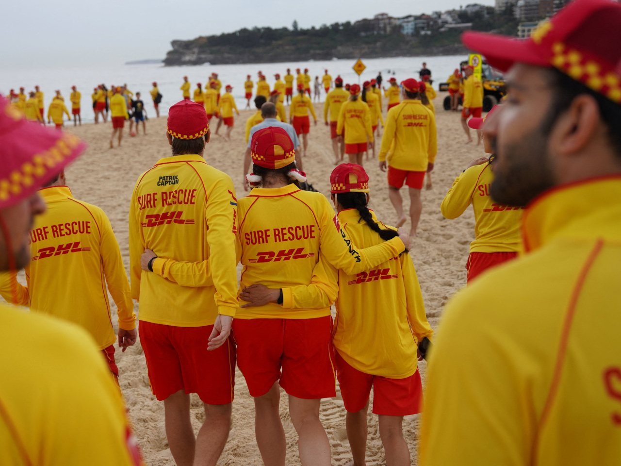 一批救生員在海灘面向大海，為遇難者默哀三分鐘。（路透社）