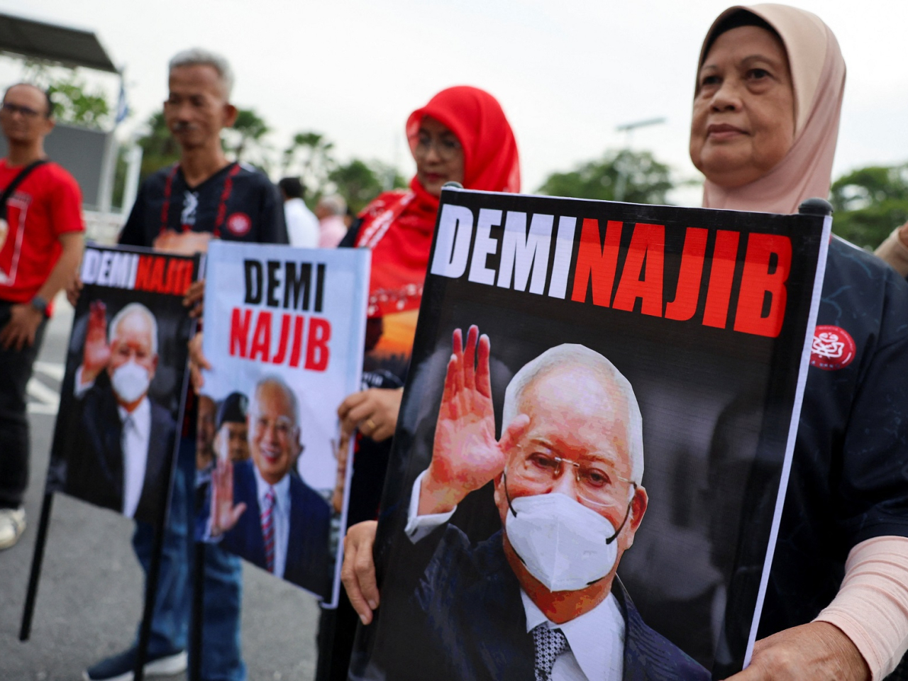 Supporters of Najib Razak hold banners featuring his portrait outside the Palace of Justice, as the high court delivers its verdict on Najib for four corruption charges and 21 counts of money laundering. Photo: Reuters