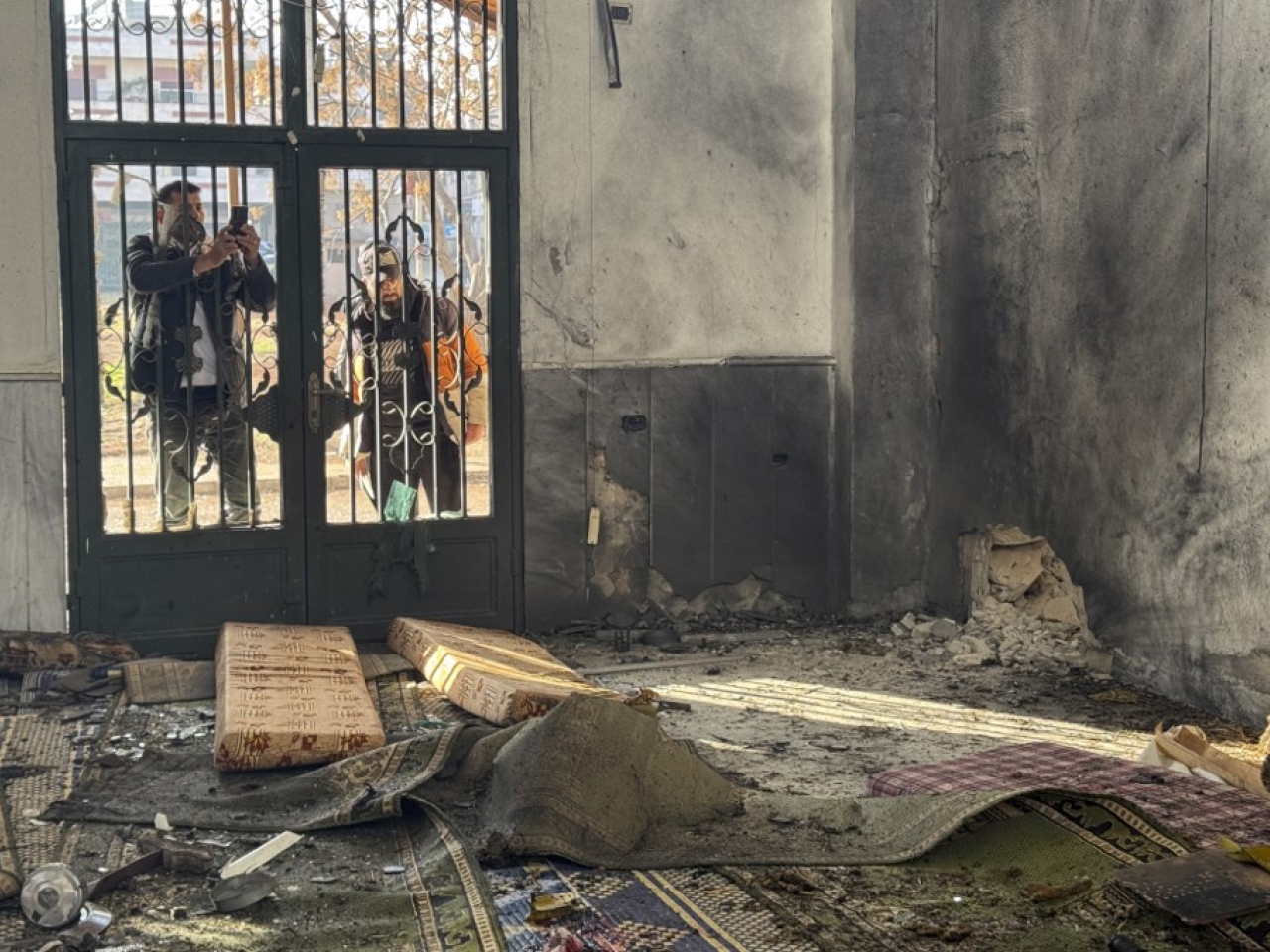 A man takes a photo of the aftermath of the explosion inside the Imam Ali ibn Abi Talib Mosque in Homs. Photo: AFP