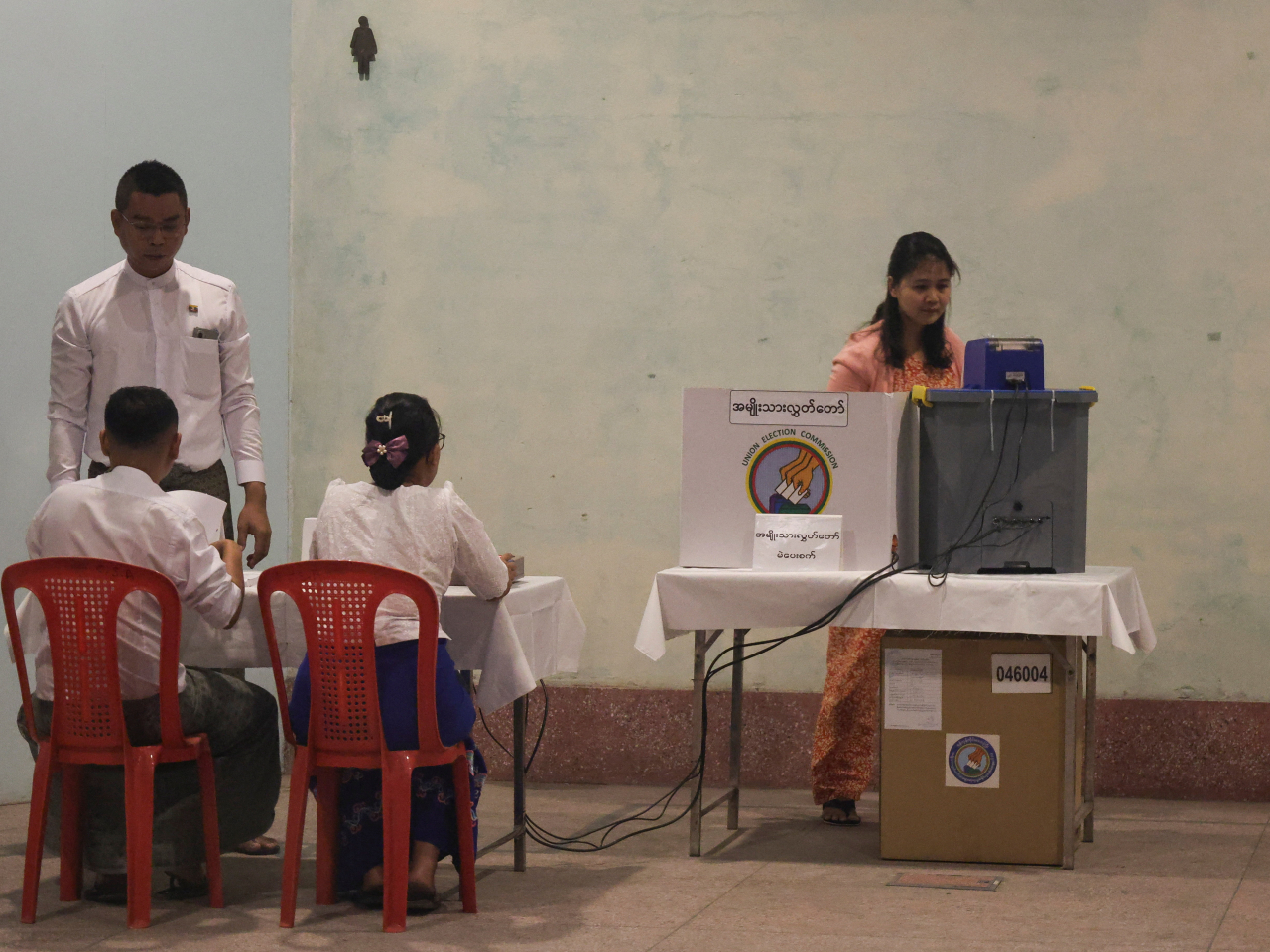 A man waits while a woman votes at Kyauktada Township Polling Station No. 1, on the day of general elections in Kyauktada, Myanmar. Photo: Reuters
