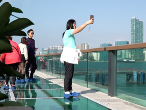 進入玻璃觀景台的人士要穿上由場地提供的鞋套，站在玻璃面可以看到腳下的維港。（林紹鋒攝）