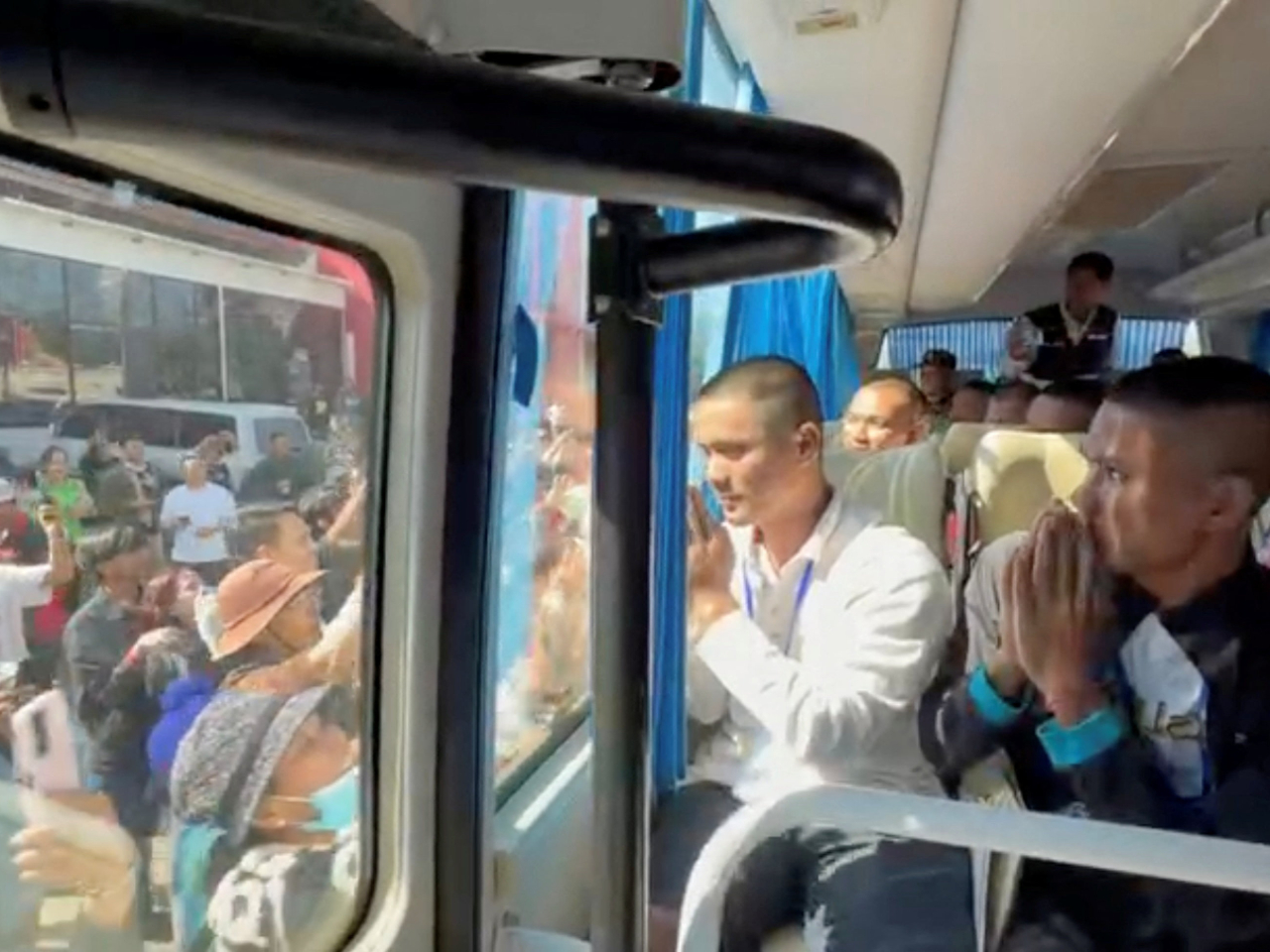 18名柬埔寨士兵在泰國登上旅遊巴，期間向窗外的人揮手。（路透社）