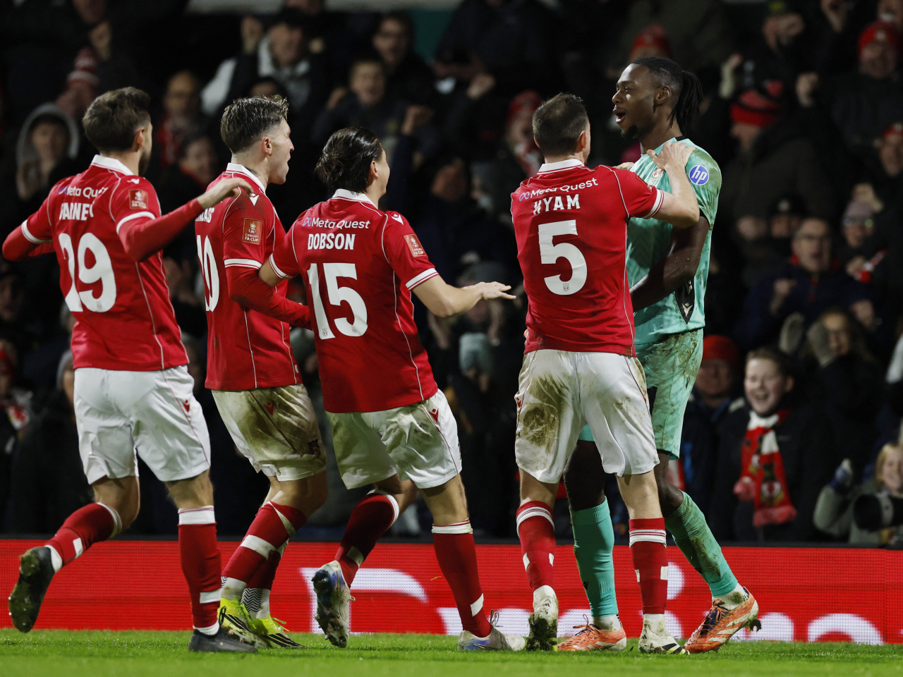 Wrexham players converge on Arthur Okonkwo after the goalkeeper wins the penalty shootout for the team against Nottingham Forest. Photo: Reuters