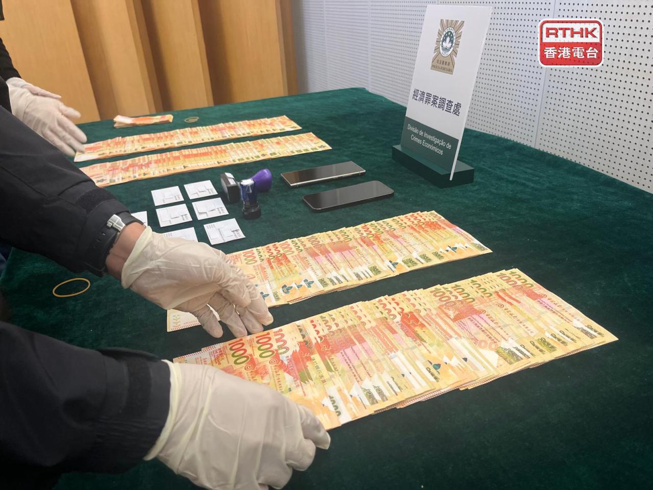 司警展示在拘捕港人夫婦時搜到的公司印章、卡片、手機和20多萬港元現金等證物。（鄭月明攝）