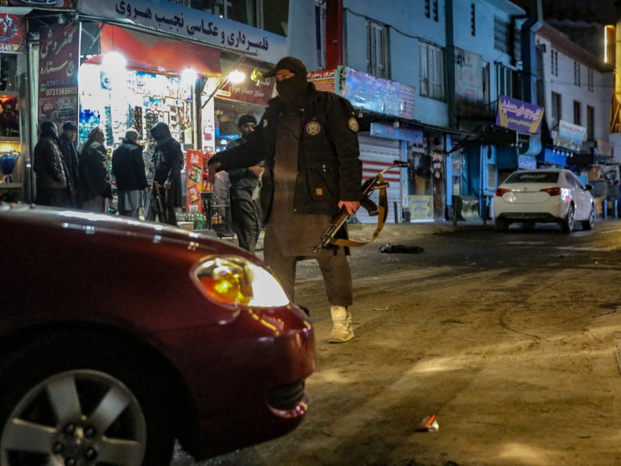 塔利班武裝人員在爆炸現場附近截查汽車。（法新社）