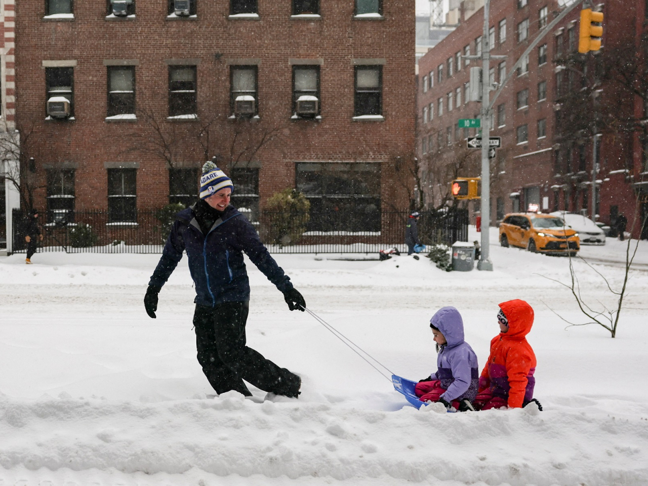 A parent pulls his children on a sled along a sidewalk in New York City. Photo: Reuters