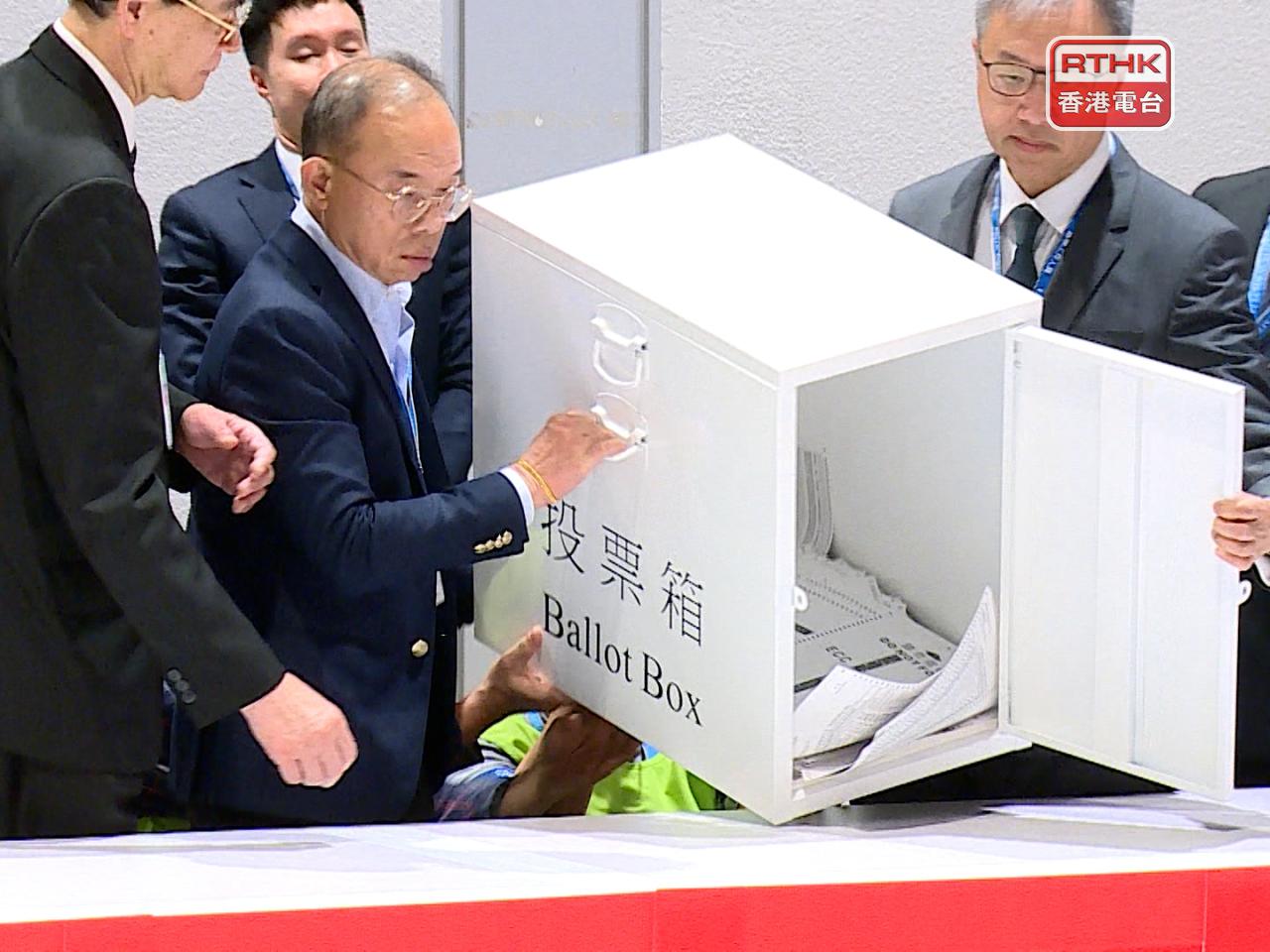 曾國衞(左二)及選管會主席陸啟康等，在去年12月立法會選舉中，在會展的中央點票站倒出票箱中選票。（港台圖片）