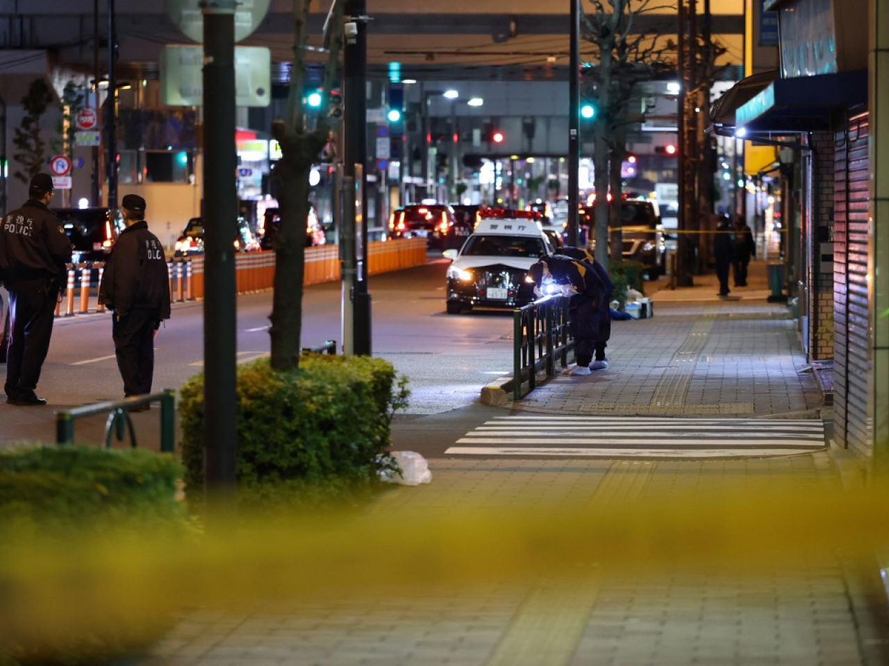 Investigators go through the scene where five Chinese and Japanese were robbed as they were about to load the cash-filled suitcases into a car. Photo: AFP