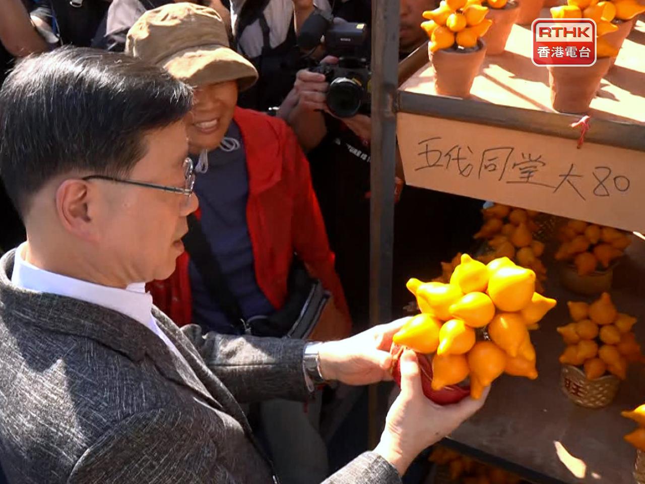 李家超到一檔花檔購買了一盆「五代同堂」。（鍾家銘攝）