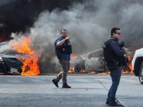 Police officers secure the area where vehicles were set on fire by organised crime members to block a road in Zapopan, Mexico. Photo: Reuters