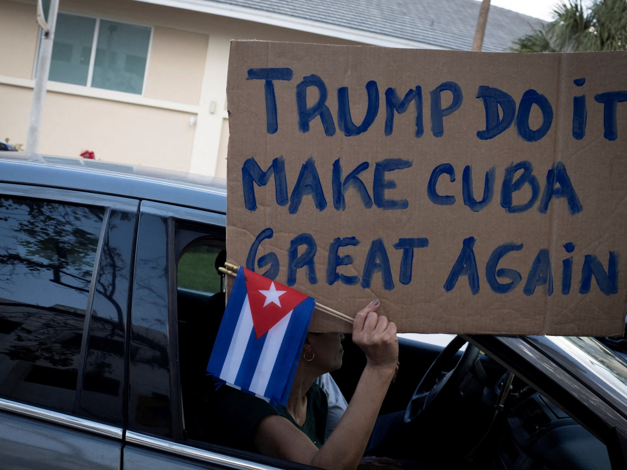 A woman holds a sign and Cuban flags as supporters of US President Donald Trump participate in a protest against Cuba's government, in Miami, Florida. Photo: Reuters
