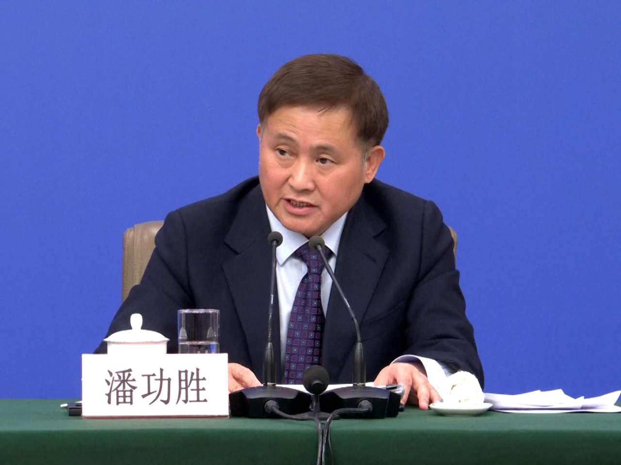 潘功勝強調，影響匯率的因素複雜，受到突發事件、地緣政治、貨幣政策和金融市場等影響。（央視截圖）