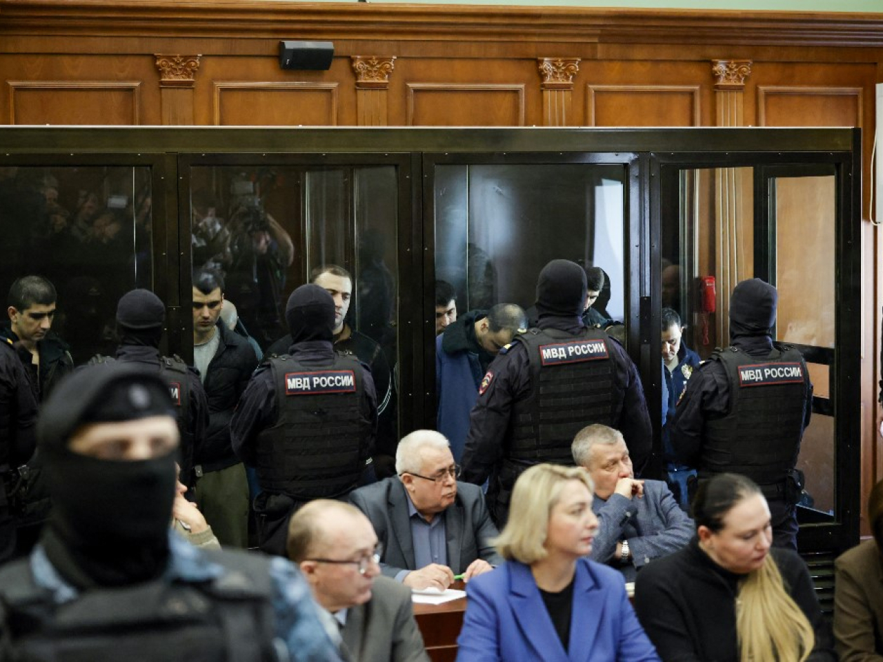 Some of the 15 men sentenced over the Crocus concert hall attack are seen through the glass box in which they are held while attending court in Moscow. Photo: AFP