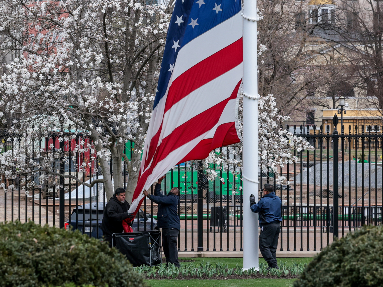 白宮工作人員在風暴來臨前收起國旗。（路透社）