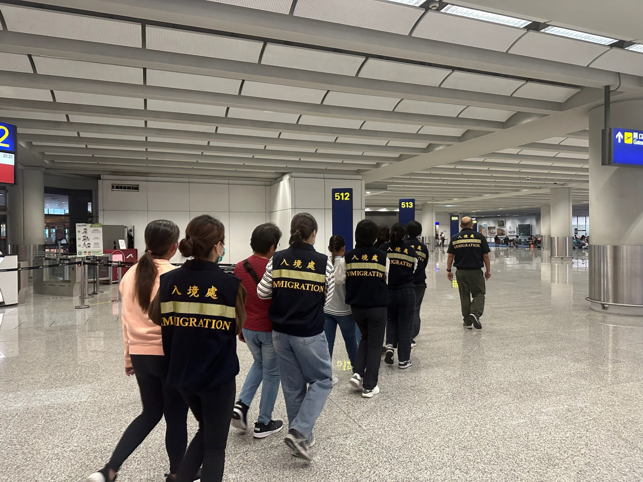 被遣返人士在入境處人員押送下離港。（政府新聞處）