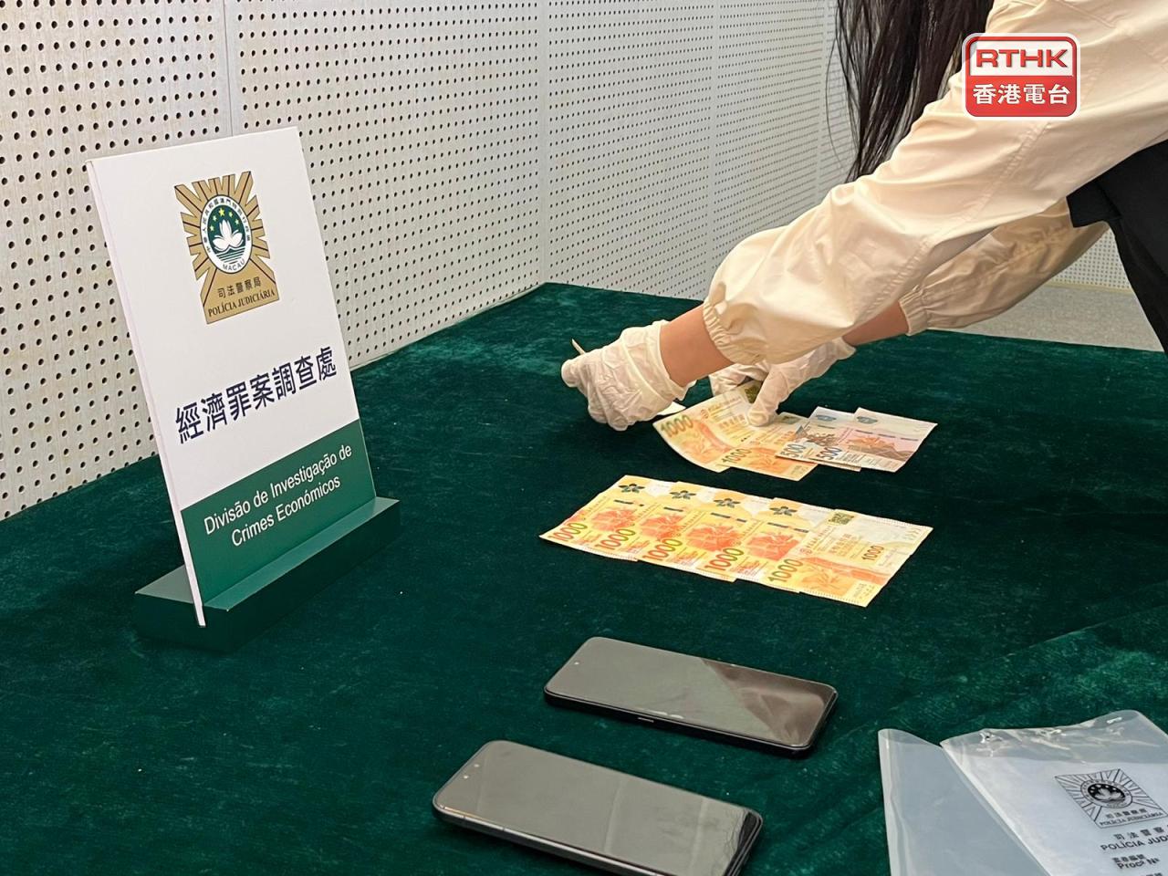 司警展示在疑犯身上搜到有偽造通訊截圖的手機和9千港元現金等證物。(鄭月明攝)