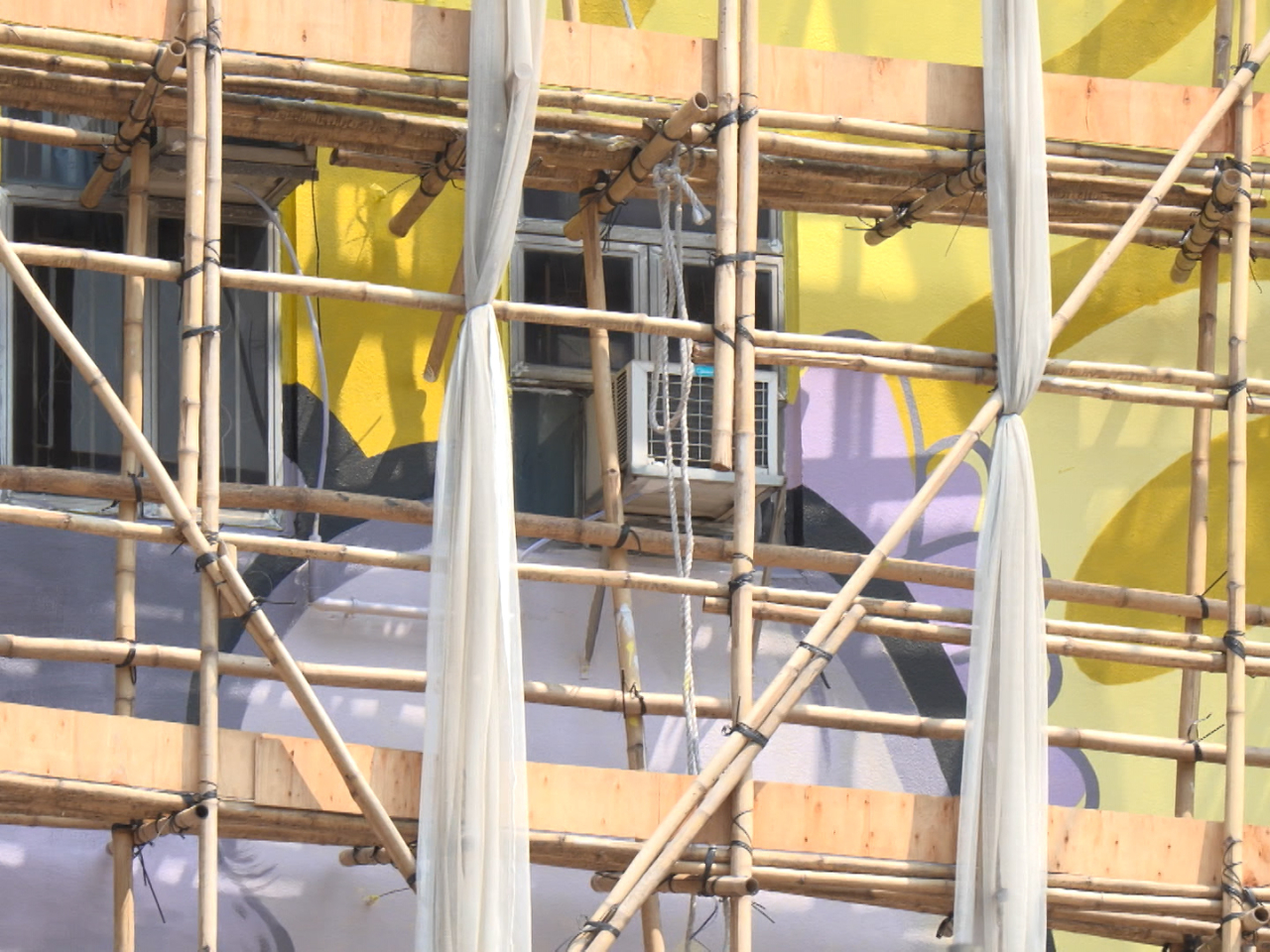 創作團隊稱，第一次在棚架上畫壁畫，高空工作期間要避開外牆冷氣機及喉管，甚有挑戰性。（鍾家銘攝）