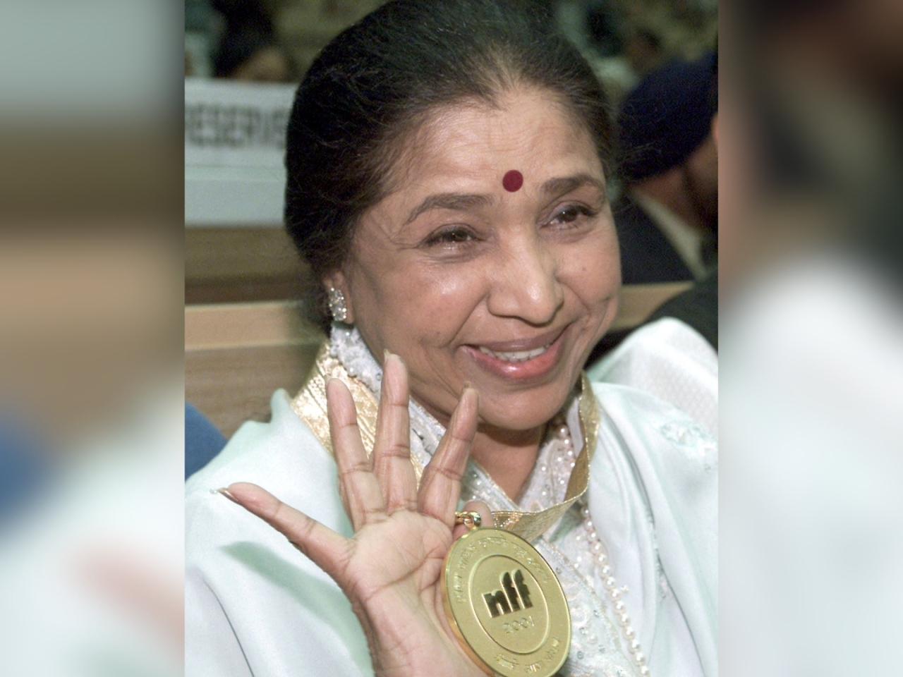 Asha Bhosle holds aloft a Dada Saheb Phalke award, a lifetime achievement during the 48th National Film Awards in New Delhi, in 2001. File photo: Reuters