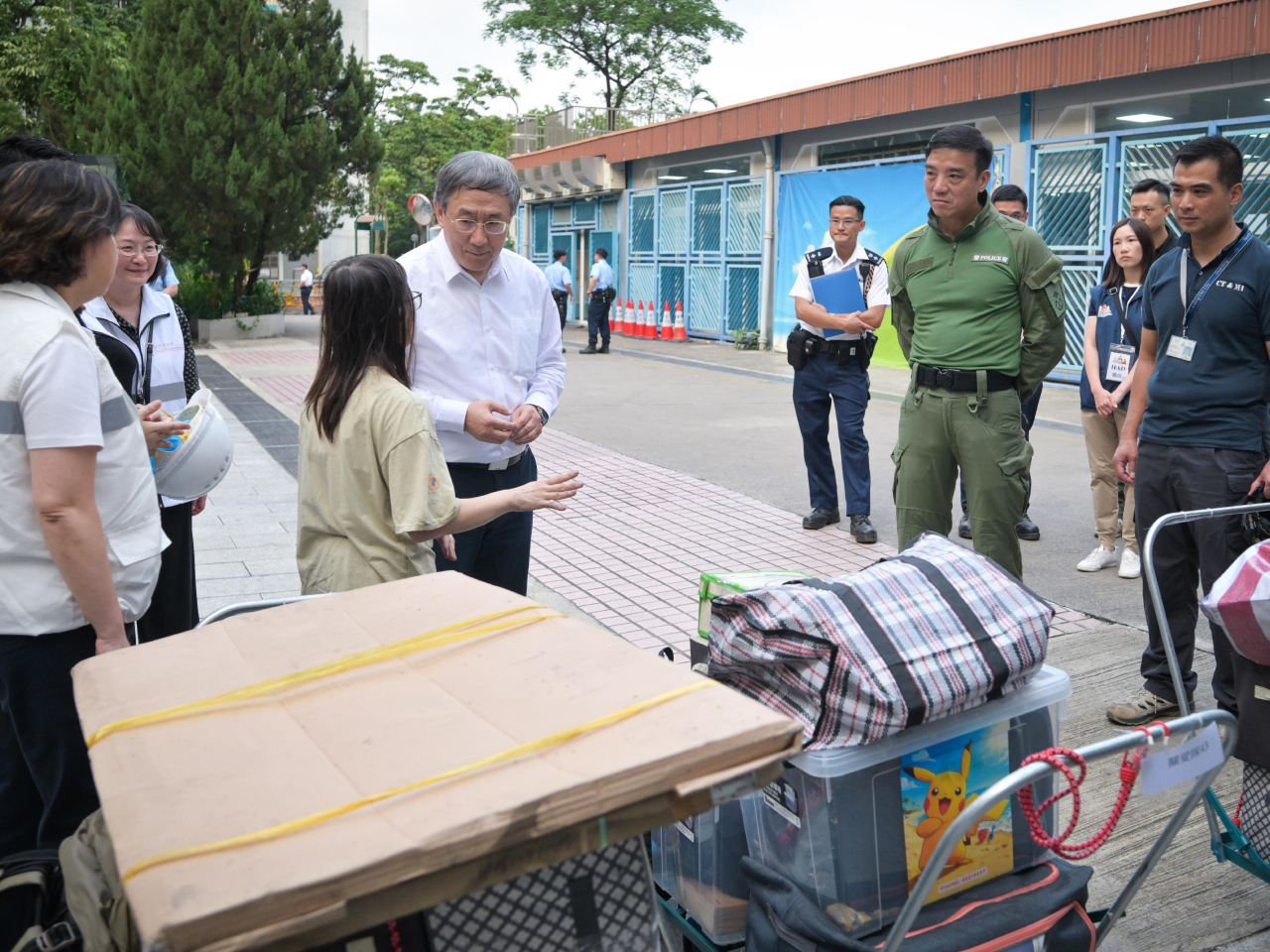 卓永興在大埔浸信會公立學校，與宏新閣一戶完成上樓、正候車離開的住戶交談。(政府新聞處)