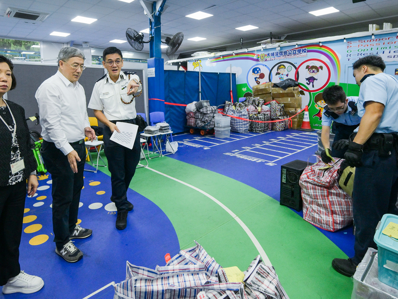 卓永興（左二）聽取江永祥（左三）講述物品儲存區的使用情況。（政府新聞處）