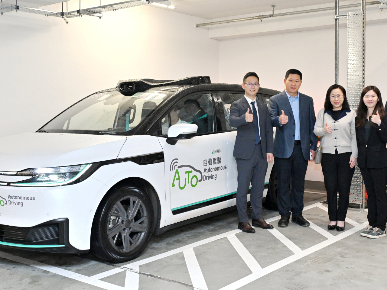 運輸署署長謝詠誼（中）在運輸署總機電工程師／自動駕駛與巴士科技鍾卓明（右一）陪同下，視察其中一個於機場島進行的測試項目，並與先導營辦人團隊合照。（政府新聞處提供）