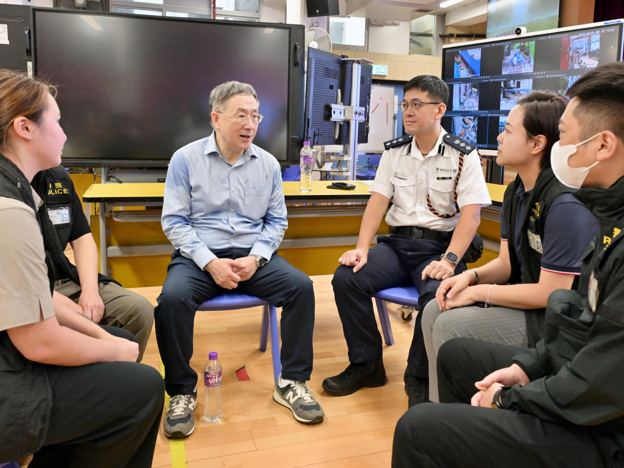 卓永興（左二）向大埔警區重案組組員了解如何處理上樓居民的求警協助個案。（政府新聞處）