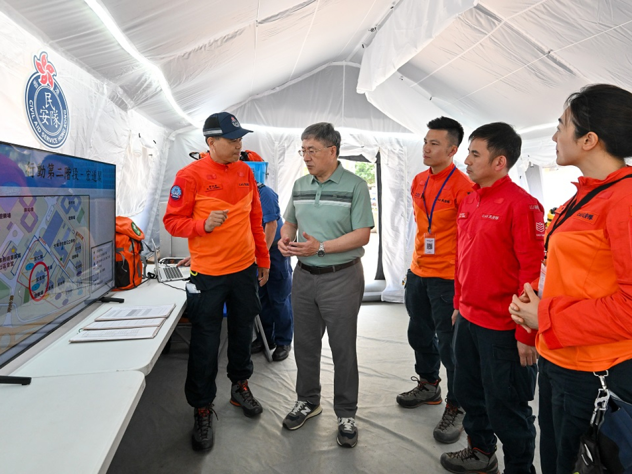 卓永興（左二）聽取民眾安全服務處總參事梁冠康（左一）講述民安隊協助居民上樓的工作和部署。（政府新聞處）