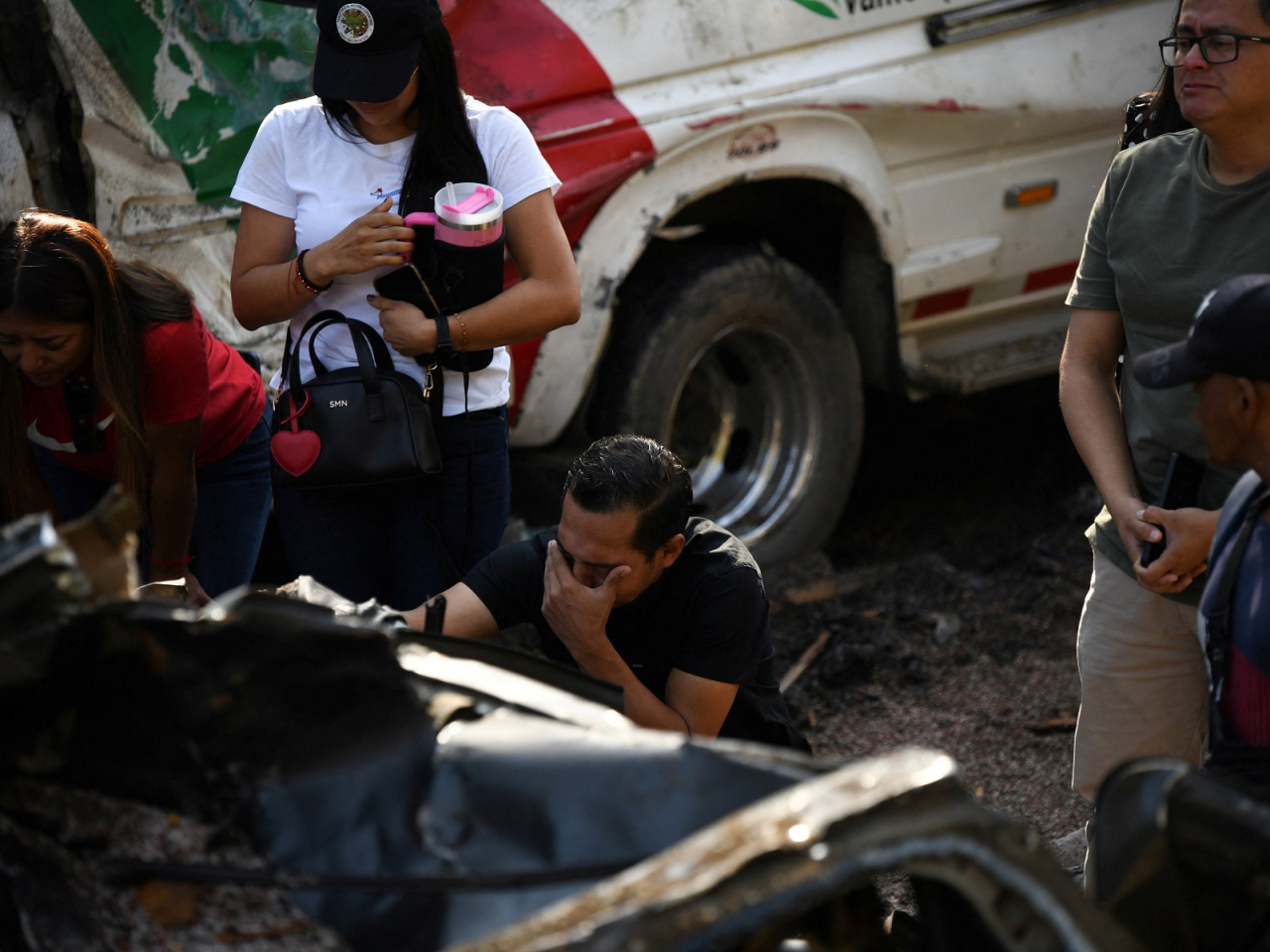 Relatives of victims mourn beside destroyed vehicles after an explosives attack killed at least 20 people on the Pan-American Highway in the El Tunel area of Cajibio, Colombia. Photo: Reuters