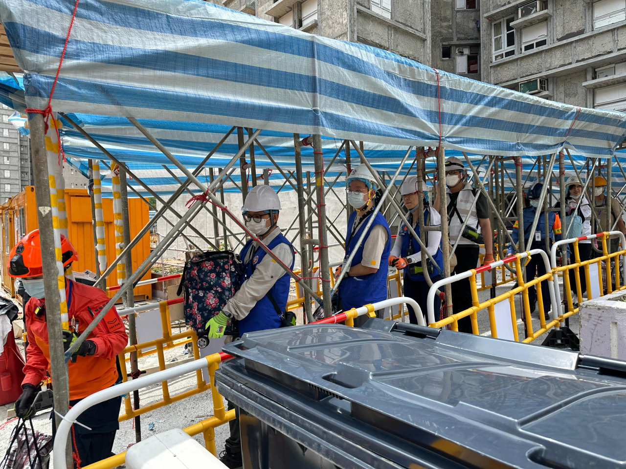 來自地政總署的動員公務員聯同民安隊隊員和地區服務及關愛隊伍義工，協助宏福苑上樓居民搬運物品落樓。（政府新聞處）