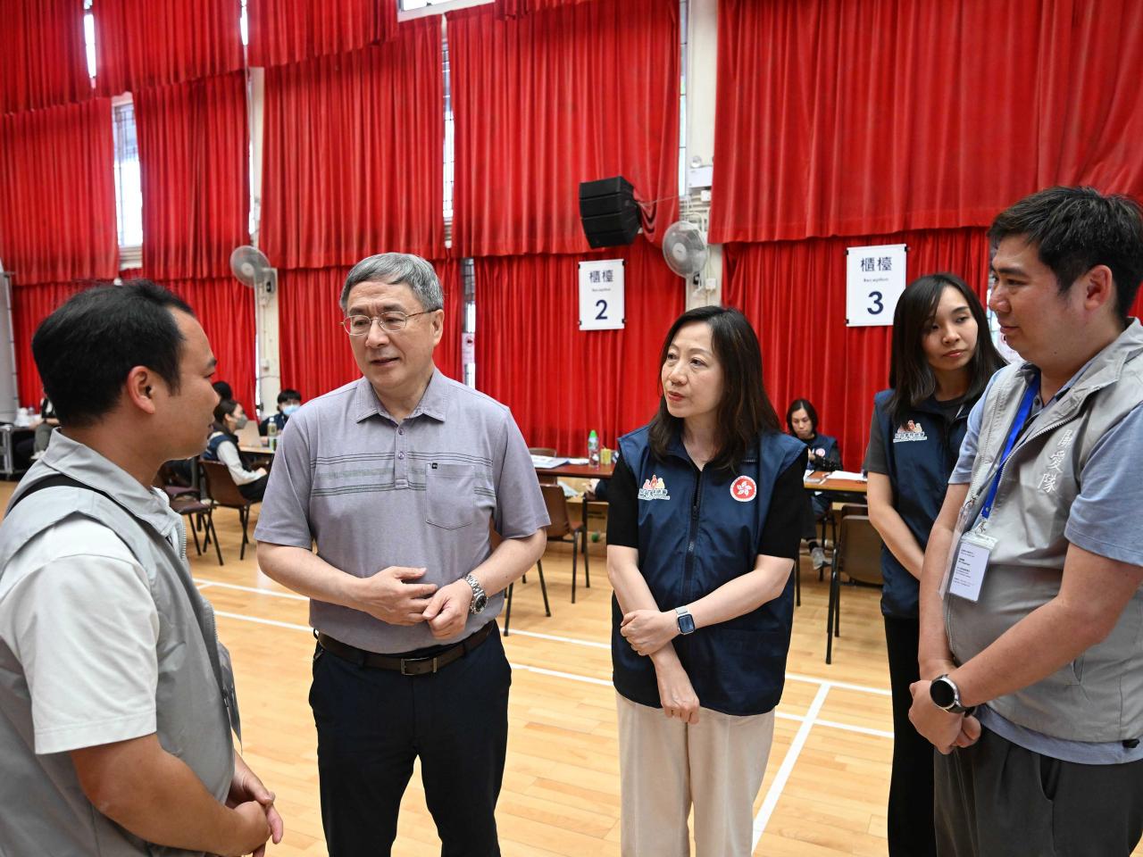 卓永興（左二）在登記中心與關愛隊義工交談。（政府新聞處）